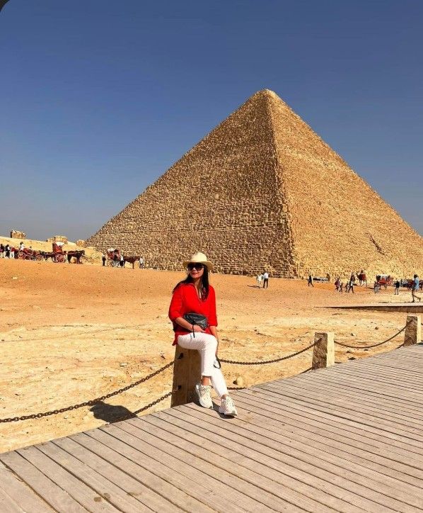 Sentada frente a la imponente Gran Pirámide de Keops